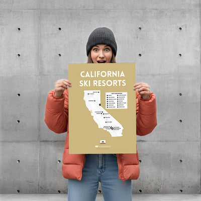 Person holding a 'California Ski Resorts' map against a concrete wall