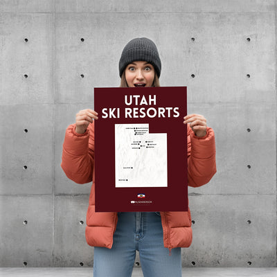 Person holding a poster with 'Utah Ski Resorts' text against a concrete wall.