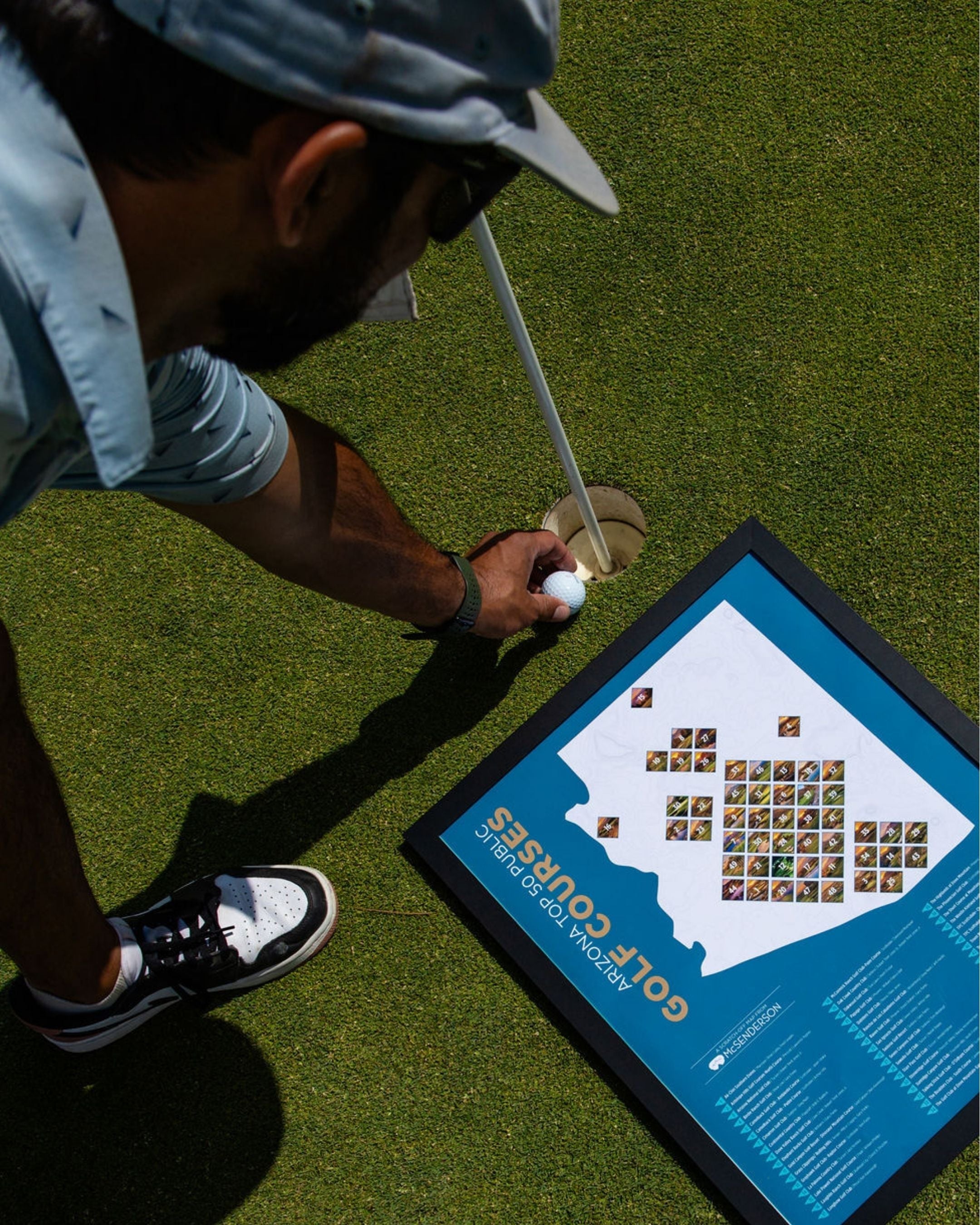 McSenderson Arizona Top 50 Public Golf Courses scratch-off map displayed on a green golf course putting surface