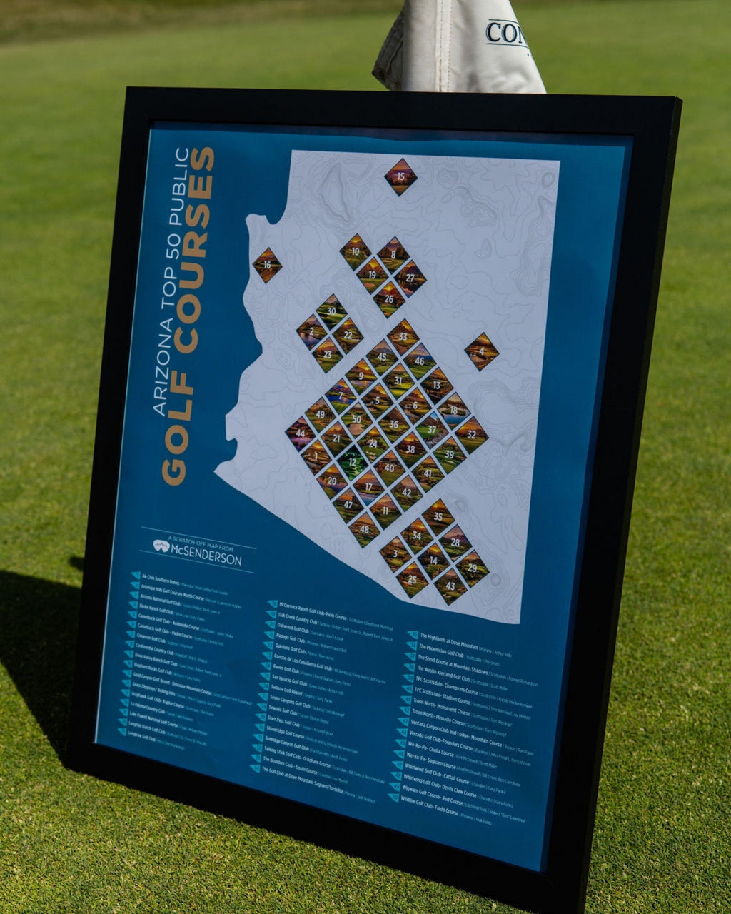 McSenderson Arizona Top 50 Public Golf Courses scratch-off map in a black frame displayed on a golf course.