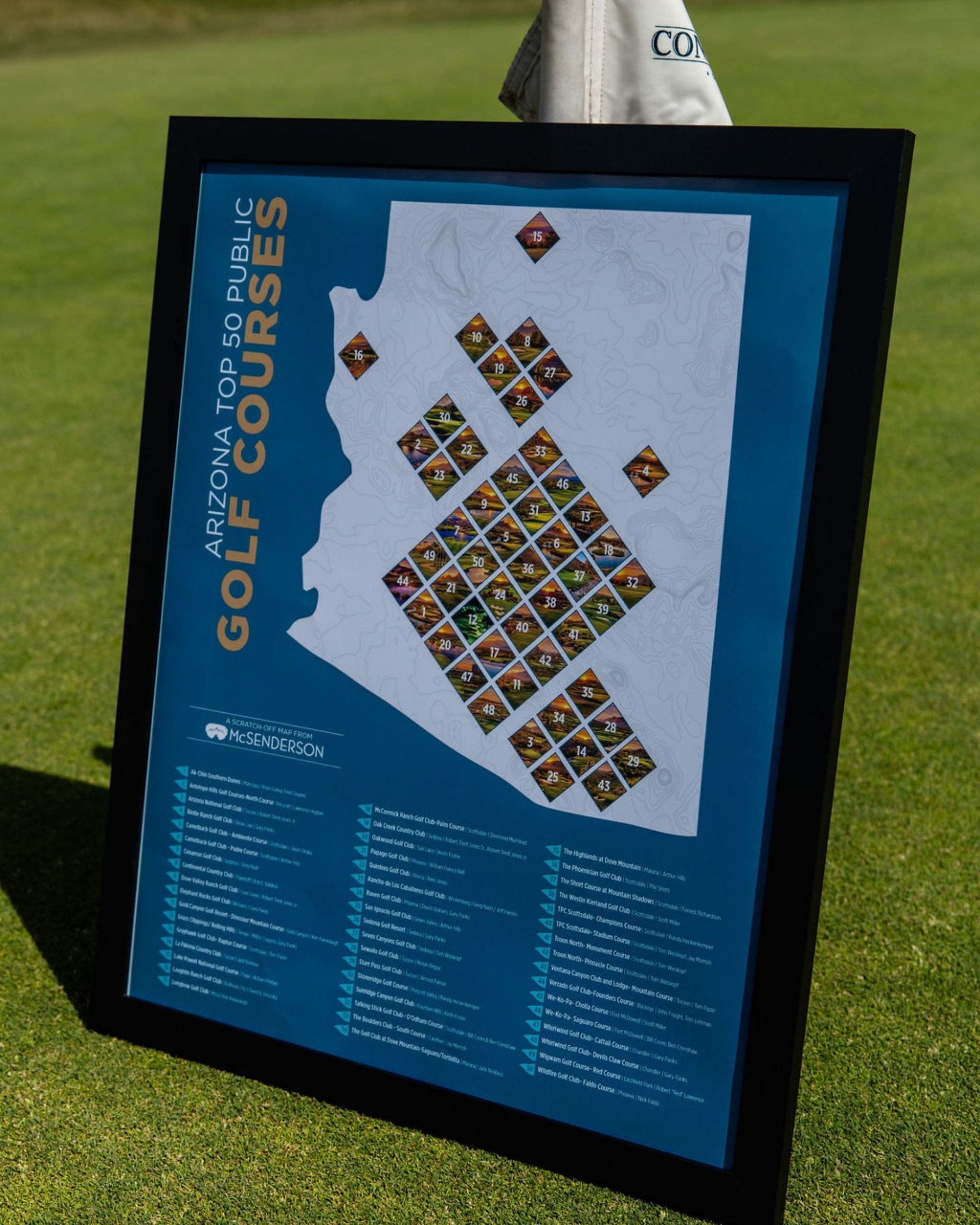 McSenderson Arizona Top 50 Public Golf Courses scratch-off map in a black frame displayed on a golf course.
